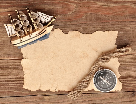 old paper, compass, rope and model classic boat on wood background