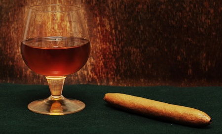 cigar and a glass of alcohol on green fabric