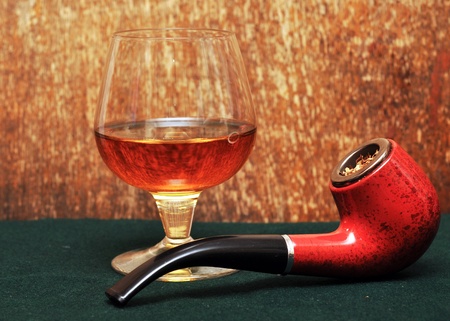 pipe and a glass of alcohol on green feltの写真素材