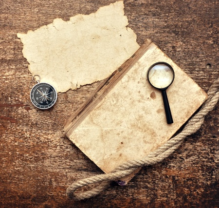 Old book, compass and magnifying glass on wood backgroundの写真素材