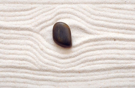 closeup of a stone on raked sand in a Japanese ornamental or zen garden. 