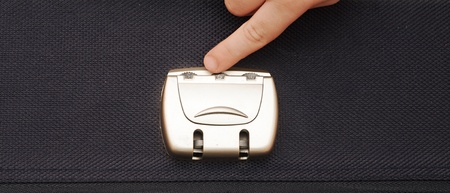 closeup photo of a combination lock on a black suitcase with child hand