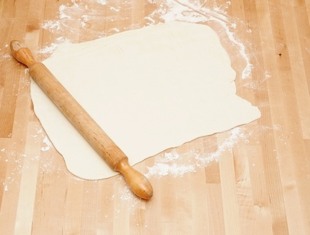 Classic wooden rolling pin with freshly prepared dough and dusting of flour. の写真素材