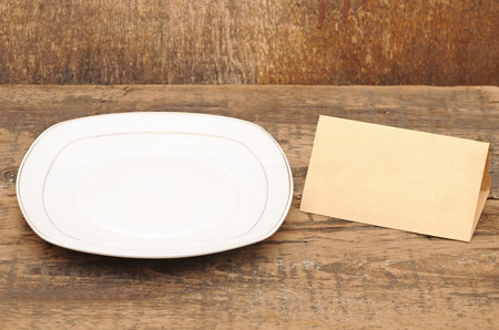 White empty plate with old paper on wood tableの写真素材