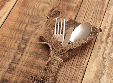 spoon, knife and fork in rough old sacking over wood with sample textの写真素材