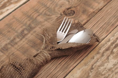 knife and fork in rough old sacking over woodの写真素材