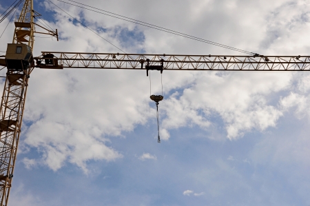 yellow construction tower crane arm against blue skyの写真素材