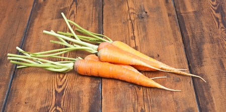 Freshly washed whole carrots on old wooden tableの写真素材
