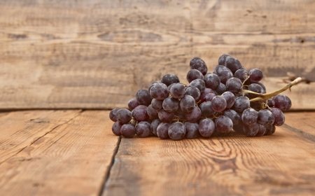 Bunch black grapes on old wooden tableの写真素材