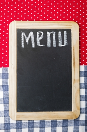 Menu title written with chalk on blackboard lying on tablecloth red polka dotの写真素材