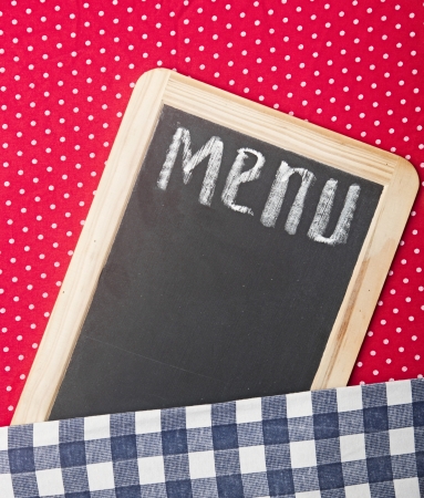 Menu title written with chalk on blackboard lying on tablecloth red polka dotの写真素材