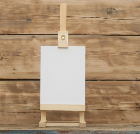 blank canvas on wooden easel againt wooden background の写真素材