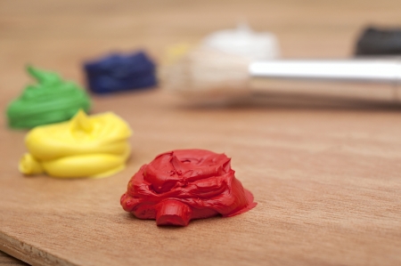 Oil paint on a palette sitting on a wood background. Focus on red colorの写真素材