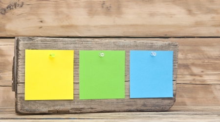 colorful reminder notes attached on a old wooden signboardの写真素材