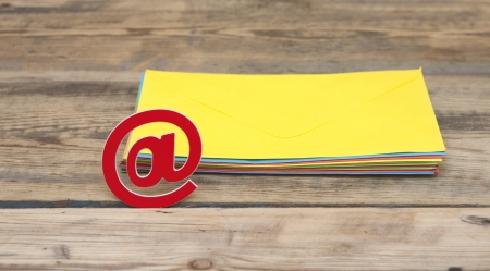 E-mail symbol and pile colorful envelopes on old wooden background の写真素材