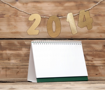 two thousand fourteen New Year number decoration hanging on rope over blank desk calendarの写真素材