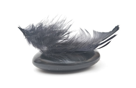 Feather balancing on stack of black stones - harmony or equilibrium concept の写真素材