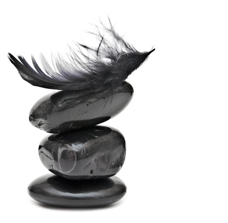 Feather balancing on stack of black stones - harmony or equilibrium concept の写真素材