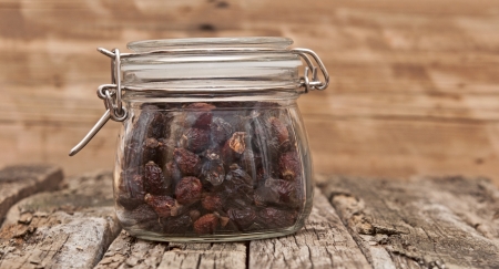 Rosehip in a glass jar on a wooden table. の写真素材