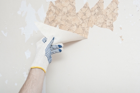 Hand removing wallpaper from wall の写真素材