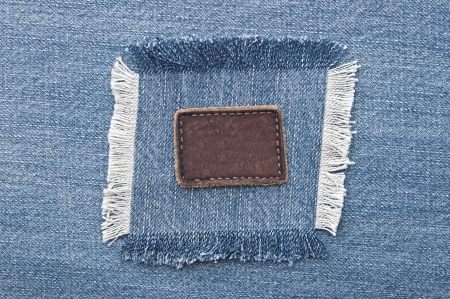 Blank leather jeans label sewed on a blue jeans. Can be used as background for your text. 