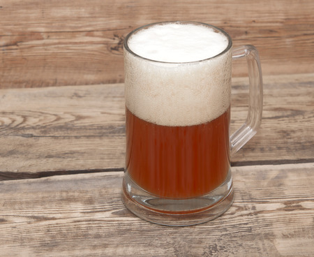 Mug of beer close up on wooden table の写真素材