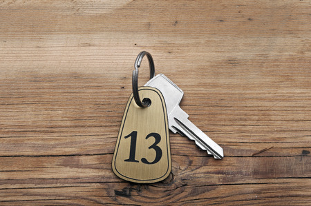Closeup of an key of room number 13 with key on a wooden deskの写真素材