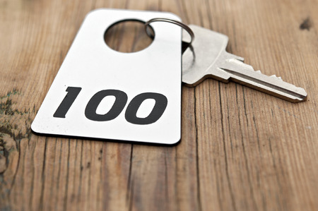 Hotel suite key with room number 100 on wood tableの写真素材