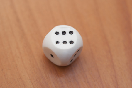 single dice displaying six on a vintage wood plank