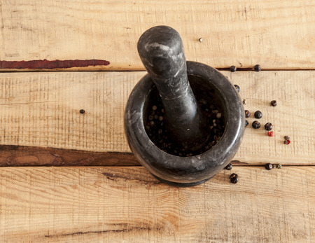 Mortar and pestle with pepper and spices on wooden tableの写真素材