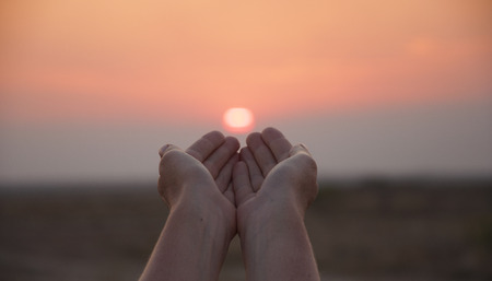hands on sunset background, the sun in handの写真素材