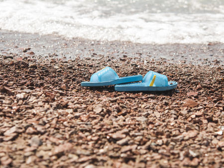 blue slippers on the sand beach with relaxing wavesの写真素材