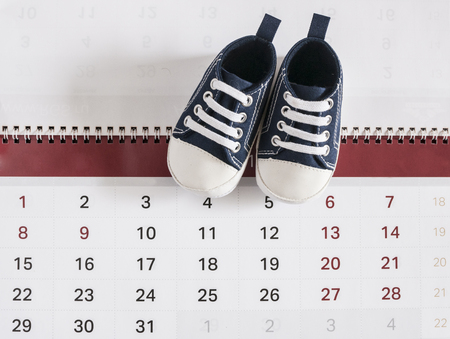 Selected due date in the calendar and detail of baby shoesの写真素材