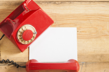 Dirty red vintage phone on pine wooden table.の写真素材