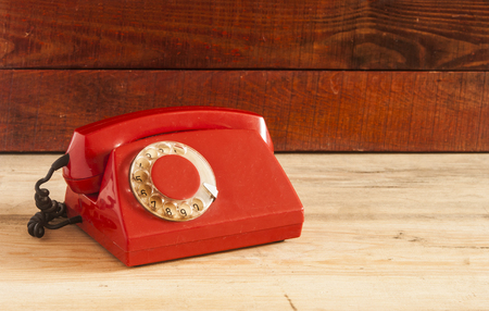 Dirty red vintage phone on pine wooden table.の写真素材