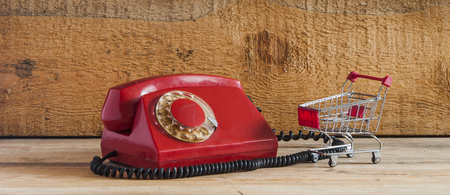 Dirty red vintage phone on pine wooden table.の写真素材