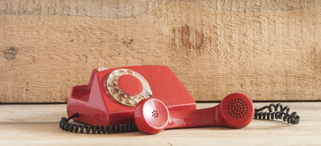 Dirty red vintage phone on pine wooden table.の写真素材