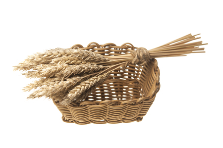 Sheaf of wheat in a wicker basket isolated on whiteの写真素材
