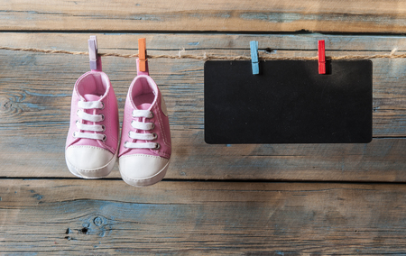 Baby shoes hanging on the colorful clothesline over wooden backgroundの写真素材