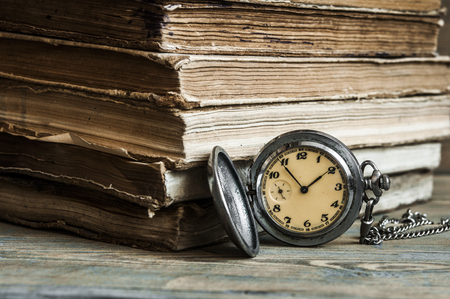 Vintage books and pocket watch on a wooden desk の写真素材