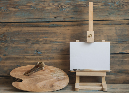 White empty artistic canvas on an easel for drawing images by an artist on a wood backgroundの写真素材