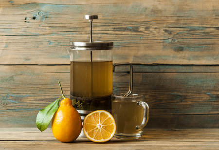 Green tea in a glass on a wooden table with yellow lemonの写真素材
