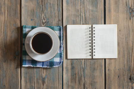 Blank notebook and cup of coffee on wood table background. top view with copy space for designの写真素材