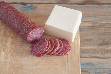 Piece of cheese and sausage on a cutting boardの写真素材