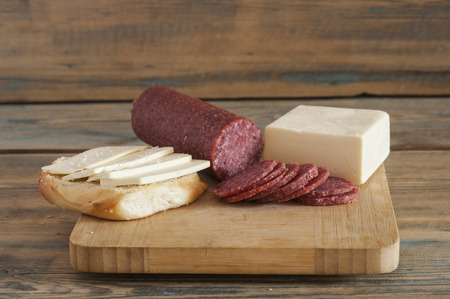 Piece of cheese and sausage on a cutting boardの写真素材