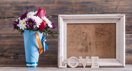 Vintage photo frame and flowers on wooden table over grunge background, Still life styleの写真素材