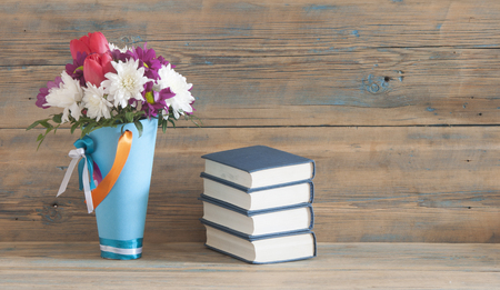 A bouquet of beautiful flowers and a stack of books on a table の写真素材
