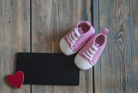 Children shoes with blank blackboard and red heart on a wood backgroundの写真素材