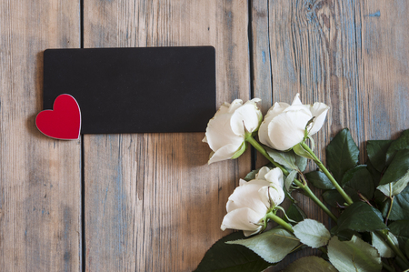 Bouquet of off white spray roses with blank blackboard on a rustic wooden background with free spaceの写真素材