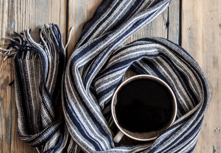 Coffee cup and warm scarf on old rustic wooden table with copy spaceの写真素材